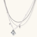 Multi-strand layered necklace set with silver chains, white pearls, star charm, heart pendant, and ornate decorative piece